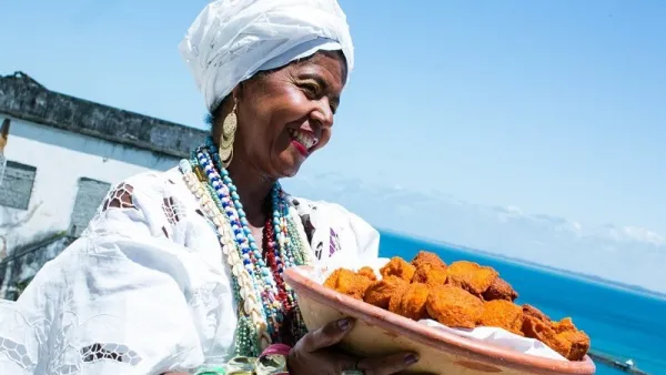 Baiana segurando tacho de acarajé.